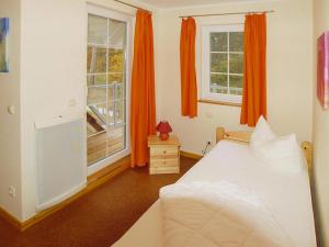 特拉森海德Semi-detached house Strandhaus II, Trassenheide的一间卧室配有床,两扇窗户配有橙色窗帘