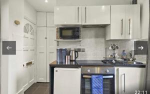 伦敦Luxury city centre Apartment的厨房配有白色橱柜和炉灶烤箱。