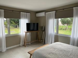 克拉罗梅科Casa claromeco的一间卧室配有一张床,两个窗户配有电视