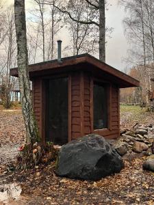 ReinaLepikumäe Holiday Home with Sauna and Hot tub for up to 16 persons的树林中的小小屋,有岩石