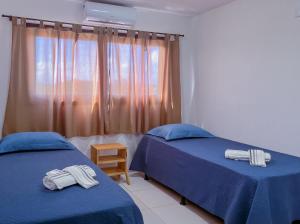 南蒂包Porto Serra Mar Flats Praia de Sibaúma- Pipa的一间卧室设有两张带蓝色床单的床和窗户。