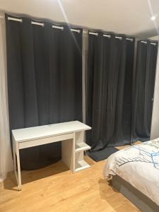 伦敦Self-contained en-suite room in Wembley的配有黑色窗帘的客房内的白色桌子