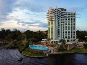 马瑙斯Hotel Tropical Executive Flat 918的一座大型建筑,设有游泳池,毗邻河流