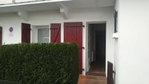 昂代Acogedor apartamento entre España y Francia.的一座白色的建筑,有红色的门和树 ⁇ 