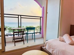 南湾南灣陽光皮小妞 Pii hostel的卧室设有1个带桌椅的阳台