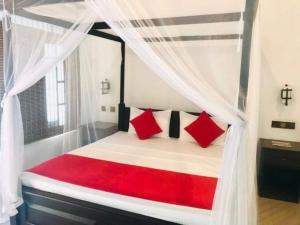 达瓦拉维Walawa Reach hotel的一间卧室配有一张带红色枕头的天蓬床