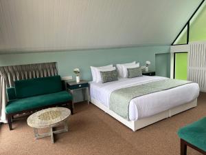 DimbulaHummingbird St.Clare Villas的一间卧室配有一张床和一把绿色椅子