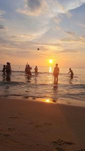 富国Nakichi Hotel Phú Quốc的一群人在日落时分在海滩上玩飞盘