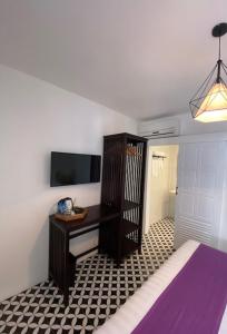 琅勃拉邦Fides Boutique Hotel的一间卧室配有一张床、一张书桌和一台电视。