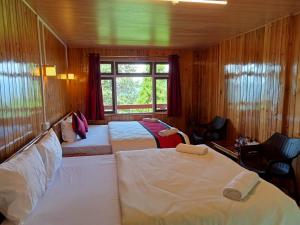 TakdāhHimalayan Cloud's Homestay的一间卧室设有三张床和窗户。