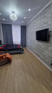 卡拉甘达Апартаменты в ЖК Мерей的卧室配有1张床和1台砖墙上的平面电视