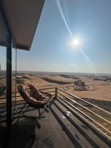 ShāhiqOman desert private camp的坐在门廊上的藤椅,眺望着沙漠