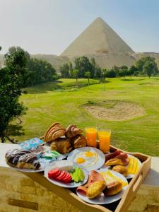 开罗Glamour Pyramids Hotel的托盘,有金字塔背景的早餐食品