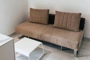 韦兰迈尔Resort Petrasia的一张棕色沙发,位于一个配有白色桌子的房间