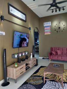 马六甲Amani Homestay的客厅配有沙发和墙上的电视