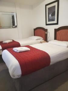布莱克浦The Melville Hotel - Central Location的配有红白毯子的酒店客房内的两张床