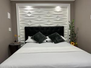 阿拉亚尔-杜卡布Flat Restinga的卧室配有一张带黑色枕头的大型白色床。