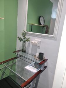 Beacon BayEland Place Self Catering Guest House的玻璃桌,墙上挂着镜子和时钟