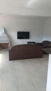 若阿诺波利斯Recanto do Sol的客厅设有一张棕色沙发,配有电视