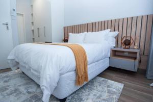 哈博罗内Luxe Lumiere @ The Habitat Alpha的卧室配有一张白色大床和木制床头板
