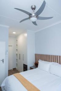 哈博罗内Luxe Lumiere @ The Habitat Alpha的卧室配有吊扇和白色的床。