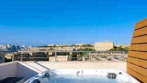 弗洛里亚纳Tritoni Valletta Boutique Hotel的阳台设有浴缸,享有城市景观。