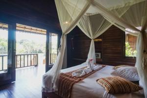 蓝梦岛Abian Huts Dream Beach Lembongan的一间卧室设有一张天蓬床和一个阳台