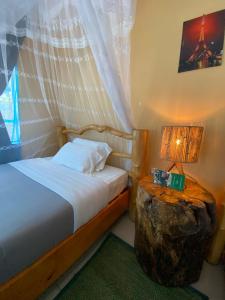KibuyeSpa Shallum的一间卧室配有一张床和一张带台灯的木桌