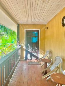 罗阿坦Island style home, low key rental的门廊配有两把椅子、一张桌子和闹钟