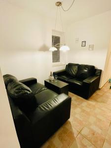 拉多夫吉卡Riverhouse apartment的客厅配有两张黑色皮革沙发和一张桌子