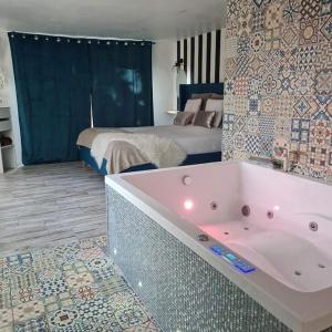 SoucellesL’Appar(T) du Grand Bois - Jacuzzi -的带浴缸的浴室和1间带1张床的卧室