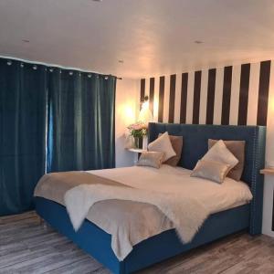SoucellesL’Appar(T) du Grand Bois - Jacuzzi -的卧室内的蓝色床,配有蓝色窗帘