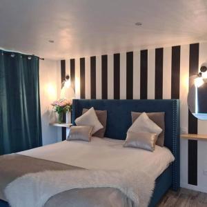 SoucellesL’Appar(T) du Grand Bois - Jacuzzi -的一间卧室配有一张蓝色的床和条纹墙