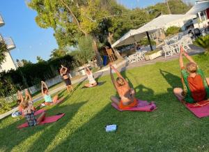 托雷圣乔万尼乌Villaggio Poseidone Beach Resort - Hotel的一群在草地上做瑜伽的孩子