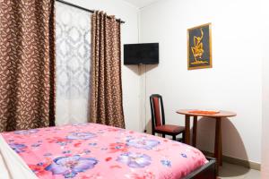 KasoaVillage Francophone Hotel的卧室配有1张床、1张桌子和1把椅子