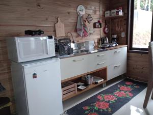 大普拉亚Tiny House Canjerana- Morro do Eurico - Praia Grande-SC的厨房配有冰箱和微波炉。
