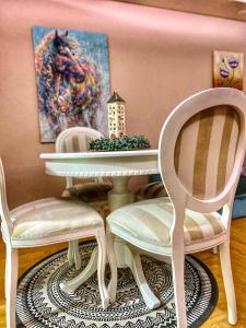 斯雷姆斯卡米特罗维察Apartman Diana的用餐室配有两把椅子、一张桌子和一幅画