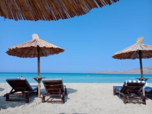 哈尔基斯Luxurious 6 bedroom villa In a great location的海滩上的两把椅子和遮阳伞