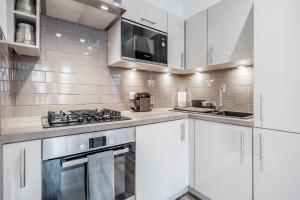 伦敦Bright & Modern 2-Bed Notting Hill Apartment的厨房配有白色橱柜和炉灶烤箱。