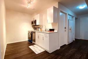 温尼伯Afan Home of Joy的厨房铺有木地板,配有白色橱柜。