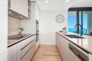 黄金海岸Breathtaking Burleigh Beach Abode的厨房配有白色橱柜和带水槽的台面