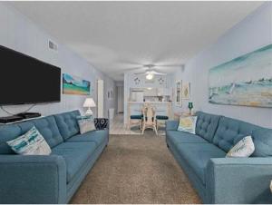默特尔比奇Blue Beach Myrtle的客厅配有蓝色的沙发和平面电视。