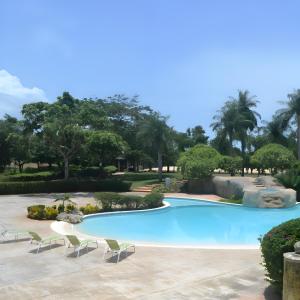 璜多里奥Majestuosa villa en Juan Dolio, Guavaberry Golf & Country Club的一座带椅子和树木的游泳池
