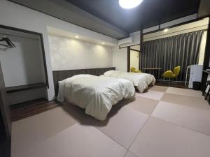 佐渡市志屋日式旅馆的一间卧室配有两张床和一张桌子及椅子