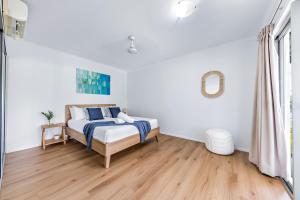 埃尔利海滩Casa Ava Airlie的一间铺有木地板的白色卧室,配有一张床