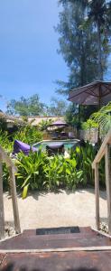吉利阿尔Purple Beach - Maïthélia - Gili Air的一个带椅子和遮阳伞的庭院和一个游泳池