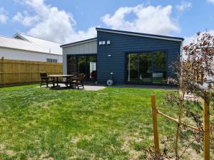 帕拉帕拉乌穆Sunshine Haven - New 3-Bedroom 4-Beds in Paraparaumu的院子里带桌子的蓝色房子