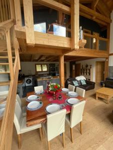 莱德萨阿尔卑斯Chalet le Lotus Blanc的一间带木桌和白色椅子的用餐室