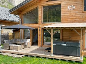 莱德萨阿尔卑斯Chalet le Lotus Blanc的木屋设有1个带遮阳伞的甲板