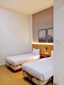 泗水Hotel Andita Syariah的配有白色床单和墙上照片的客房内的两张床